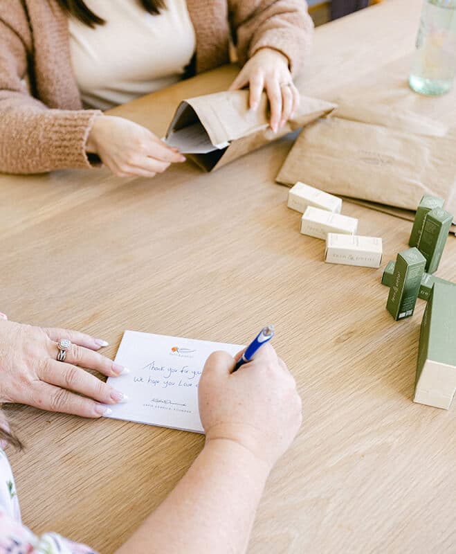 A person signing a card from Fern & Petal